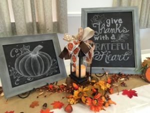 sign reading "give thanks with a grateful heart" and autumn leaves scattered on a table