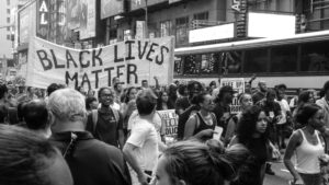 crowd of protestors carrying a black lives matter banner