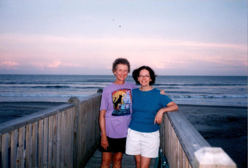Two women smile at the camera together at sunset on the beach
