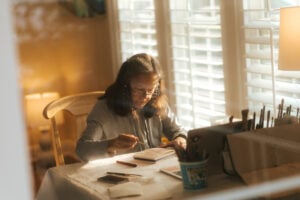 Jeanette Stokes sits at her art station inside a warmly lit house.